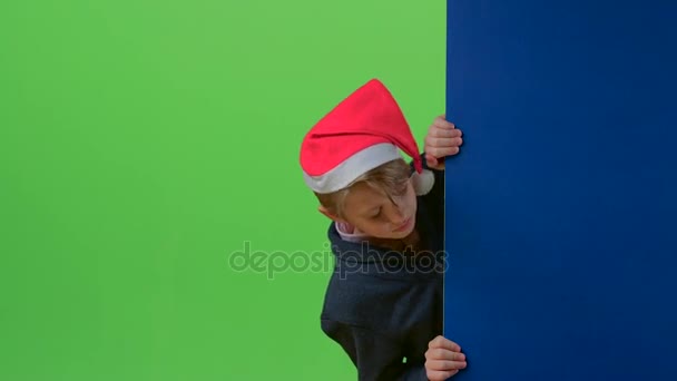 Teen in christmas hat appears from the side boards on a green screen — Stock Video