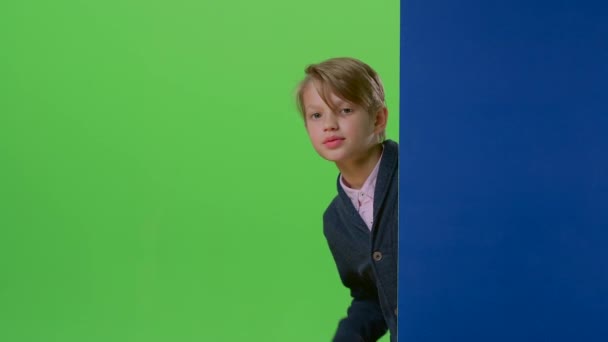 Adolescent jette un coup d'oeil derrière une planche montre la pièce et la trompette sur un écran vert — Video