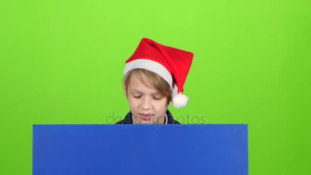 Teenager in the hat appears from a board on a green screen. Slow motion — Stock Video