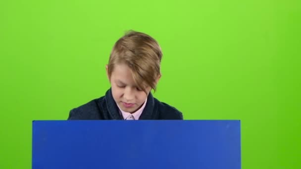 Teenager peeks out from behind the boards and shows dislike on a green screen. Slow motion — Stock Video