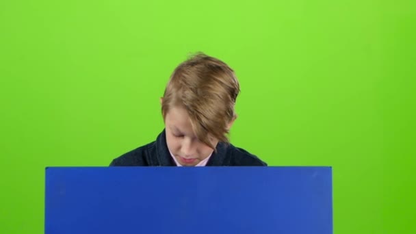 Έφηβος παίρνει επάνω και δείχνει σε έναν πίνακα σε μια πράσινη οθόνη. Αργή κίνηση — Αρχείο Βίντεο
