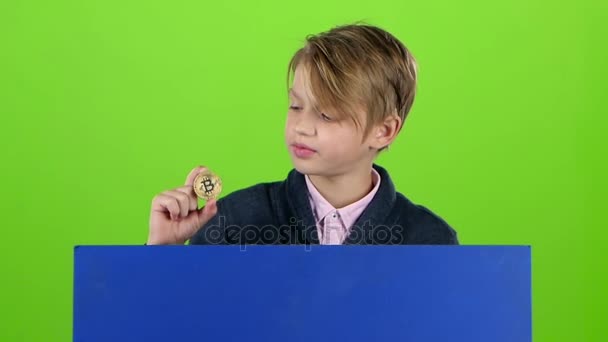 Έφηβος αγόρι σηκώνεται πίσω από το Διοικητικό Συμβούλιο με το τσιπ σε μια πράσινη οθόνη. Αργή κίνηση — Αρχείο Βίντεο