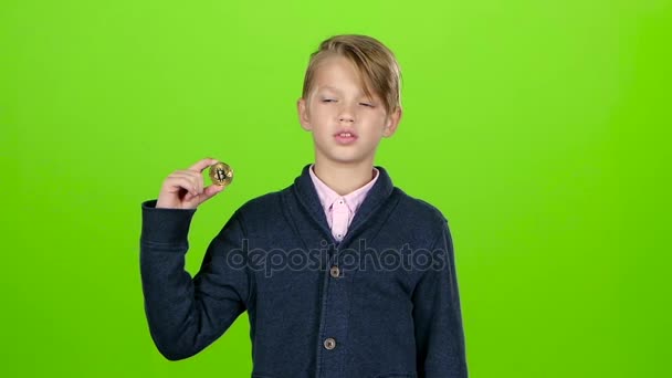 Barn pojke upp handen och visar det guldfärgade chipet på grön skärm. Slow motion — Stockvideo