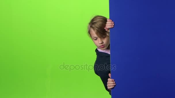 Niño se asoma desde el tablero lateral y asiente con la cabeza en la pantalla verde. Movimiento lento — Vídeos de Stock