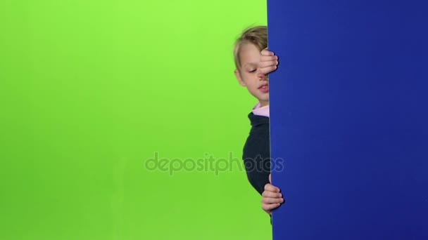 Teen peeks out from the side the boards and shows dislike on a green screen. Slow motion — Stock Video