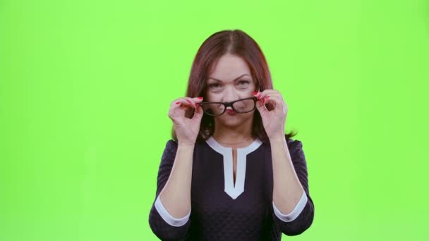 Middle aged woman with spectacles flirts in embarrassment. Green screen — Stock Video