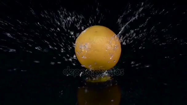 Orange spadne do vody. Černé pozadí. Zpomalený pohyb — Stock video
