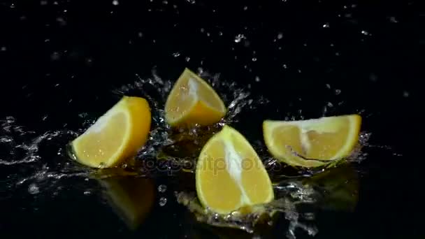 Oranje valt in het water en de einden omhoog in vier delen. Zwarte achtergrond. Slow motion — Stockvideo