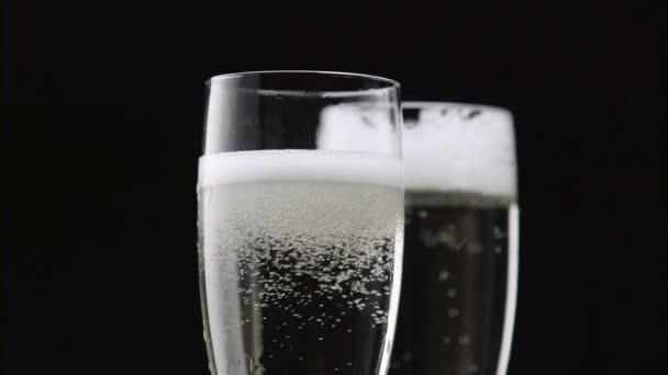 Rempli de deux verres de champagne avec des bulles blanches sur un fond noir. Gros plan 