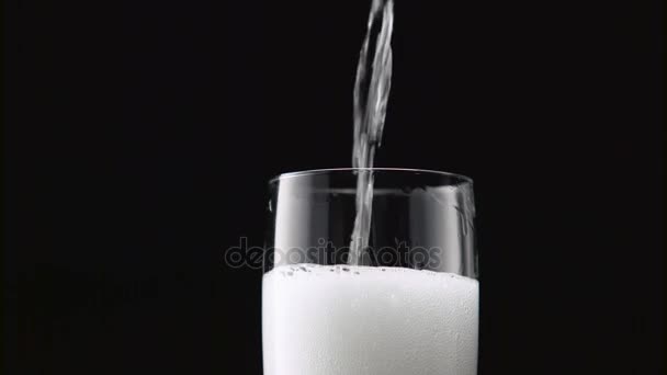 Champagne versé dans le verre. Fond noir. Gros plan 