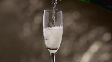 Yarısı boş bardak şampanya yeşil şişe ile doldurulur. Bokeh arka plan
