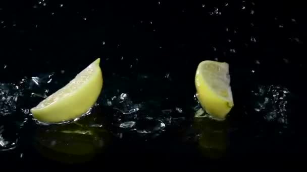 Kwartaal van citroen valt in het water. Zwarte achtergrond. Slow motion — Stockvideo