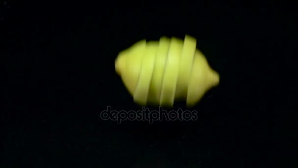 Zitrone löst sich in Scheiben, wenn sie ins Wasser fällt. schwarzer Hintergrund. Zeitlupe — Stockvideo