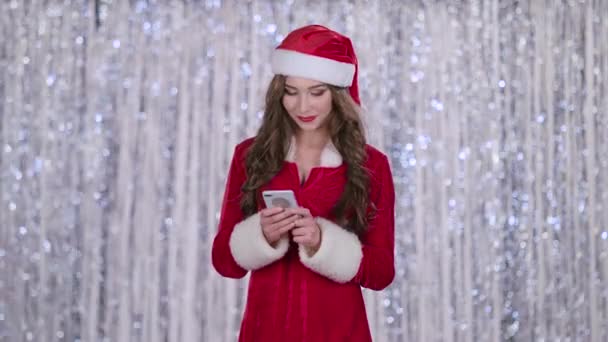 Santas assistent ser in i smartphone och leenden. Bokeh bakgrund — Stockvideo