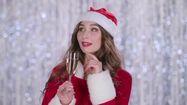 Mädchen im Anzug von Weihnachtsmann Assistent mit einem Glas in der Hand träumte. Bokeh-Hintergrund. Nahaufnahme — Stockvideo