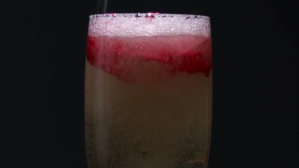 Rosebud at the bottom of the glass, the waiter pours champagne into it. Black background — Stock Video