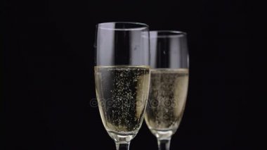 İki kadeh şampanya içinde dönen bir kabarcıkları ile. Siyah arka plan. Yakın çekim