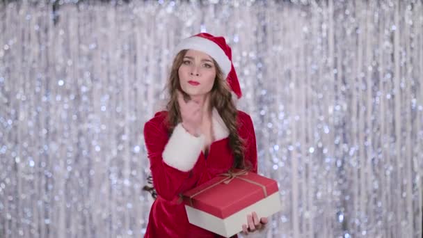 Das Weihnachtsmädchen mit einem Geschenk in der Hand zeigt den Finger leiser. Bokeh-Hintergrund. Zeitlupe — Stockvideo
