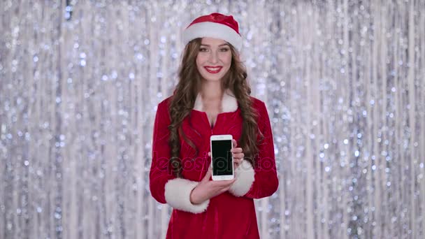 Santa dziewczyna trzyma telefon w jej ręce i spogląda w dal. Tło bokeh. Zwolnionym tempie — Wideo stockowe