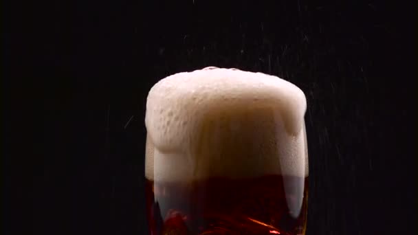 Cola, nalil do sklenice s kostkami ledu a to přeteče s pěnou tekoucí přes okraj. Černé pozadí. Detailní záběr — Stock video