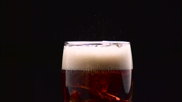 Glass of cola with ice hisses and foams on a black background. Close up — Stock Video