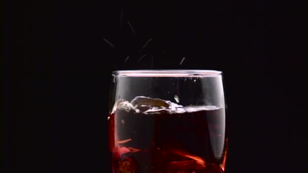 Cola sklo vynechat dvě kostky ledu. Černé pozadí. Detailní záběr — Stock video