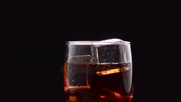 Half empty glass of cola with ice filled to the brim. Black background. Close up — Stock Video