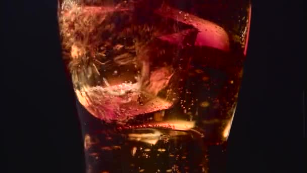 Cola füllt ein transparentes Glas, das mit Eiswürfeln gefüllt ist. schwarzer Hintergrund. Nahaufnahme — Stockvideo