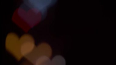 Birkaç siyah bir arka plan üzerinde renkli kalpler yanıp sönen refocusing. Bulanık bokeh