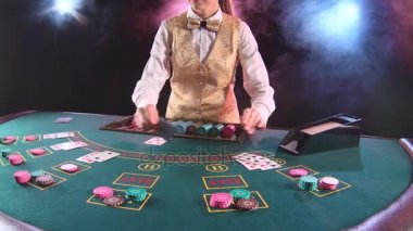 Casino çöp adam kadın altın yeleği kartları oyun masasında kart sahibinden alır. Siyah arka plan. Duman. Ağır çekim