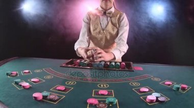 Casino çöp adam kadın poker masa üstü kartları dağıtır. Siyah arka plan. Duman. Ağır çekim