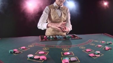 Casino çöp adam kadın kesim kartı kullanarak poker masa üstü kartları dağıtır. Siyah arka plan. Duman. Ağır çekim