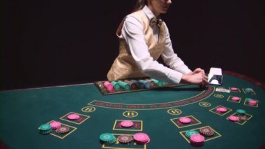 Casino kadın krupiye kartları oyun masasında kart sahibinden alır. Siyah arka plan. Ağır çekim