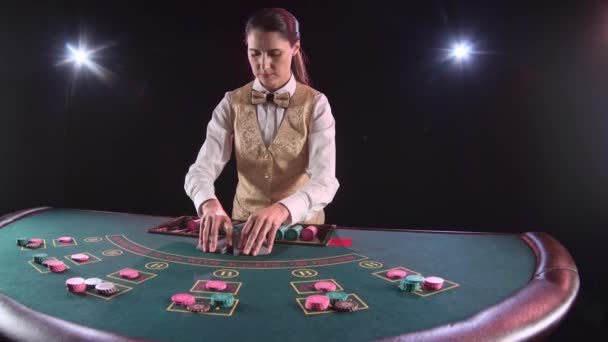 Casino distribuidor distribuye para el póquer de mesa tres cartas son el flop. Fondo negro. Movimiento lento — Vídeo de stock