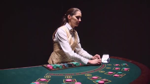 Poker spel dealern delar ut korten på ett grönt bord. Svart bakgrund. Slow motion — Stockvideo