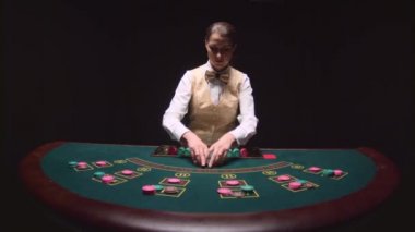Tablo poker üç kartları flop için casino kadın krupiye dağıtır. Siyah arka plan. Ağır çekim