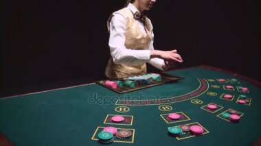 Casino kadın krupiye kesim kartı kullanarak poker masa üstü kartları dağıtır. Siyah arka plan. Ağır çekim