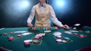 Kız Çöp Adam düzgünleştirir kartların karmaşık bir kombinasyonu ve poker oyunu fiş. Duman. Ağır çekim