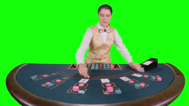 Kasino croupier perempuan berdiri di meja mengambil kartu dari pemegang kartu untuk permainan dalam poker. Layar hijau. Gerakan lambat — Stok Video
