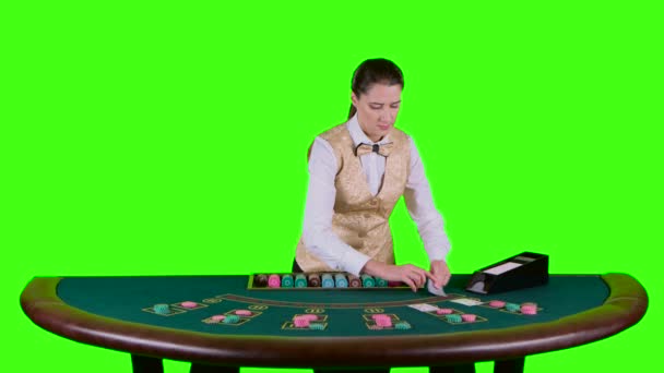 Casino croupier står bakom halvcirkelformade tabellen i en vit skjorta tar korten från kortinnehavaren för spel i poker. Grön skärm. Slow motion — Stockvideo
