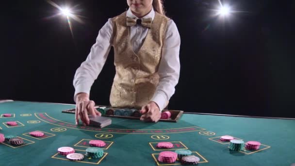 Cassino croupier mulher misturando as cartas de poker e executando truque com cartões. Fundo preto. Luz brilhante. Movimento lento — Vídeo de Stock