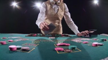 Tablo poker üç kartları flop için kumarhane krupiye dağıtır. Siyah arka plan. Parlak ışık. Ağır çekim
