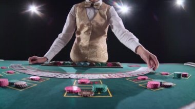 Profesyonel casino krupiye poker kartları ve performans gösteren hüner ile kartları karıştırır. Siyah arka plan. Parlak ışık. Ağır çekim