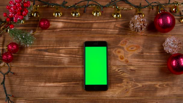 Telefon van az asztalon, mellett az új év fények. Szemközti nézet — Stock videók