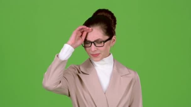 Flicka i kostym står i studion, har hon fruktansvärd huvudvärk. Grön skärm — Stockvideo
