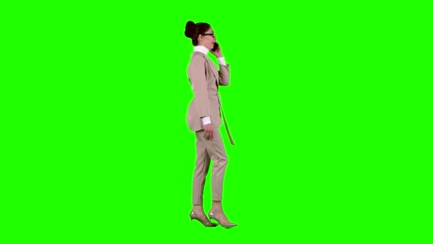 La mujer camina y habla por teléfono. Pantalla verde. Vista lateral — Vídeos de Stock