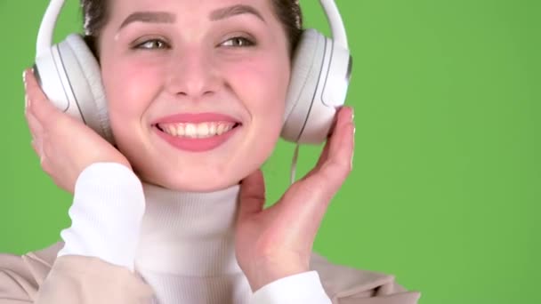 Chica escucha canciones melodiosas en los auriculares. Pantalla verde. De cerca. — Vídeo de stock