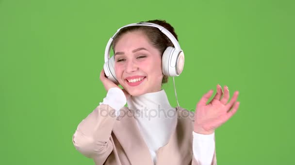 Mujer escucha canciones melodiosas en los auriculares. Pantalla verde — Vídeos de Stock