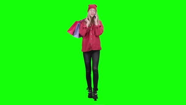 Teenager comes with bags in his hands and talks on the phone. Green screen — Stock Video