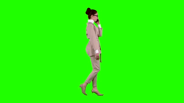 Zakenvrouw is lopend en pratend aan de telefoon. Groen scherm. Zijaanzicht. Slow motion — Stockvideo